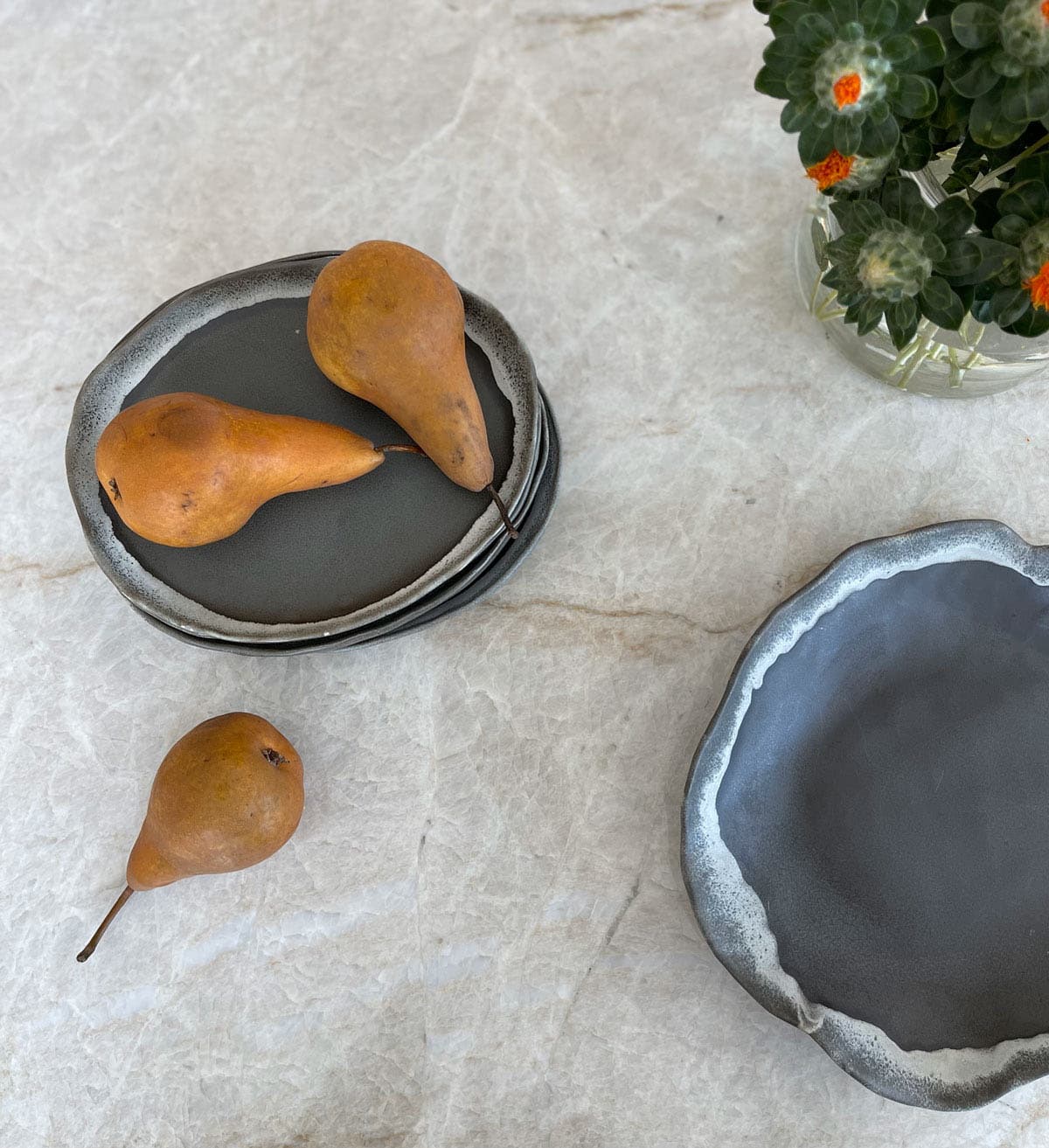 Nida Risto Interior Design in Jackson Hole designed a marble rustic kitchen counter with a ceramic plate and pears.